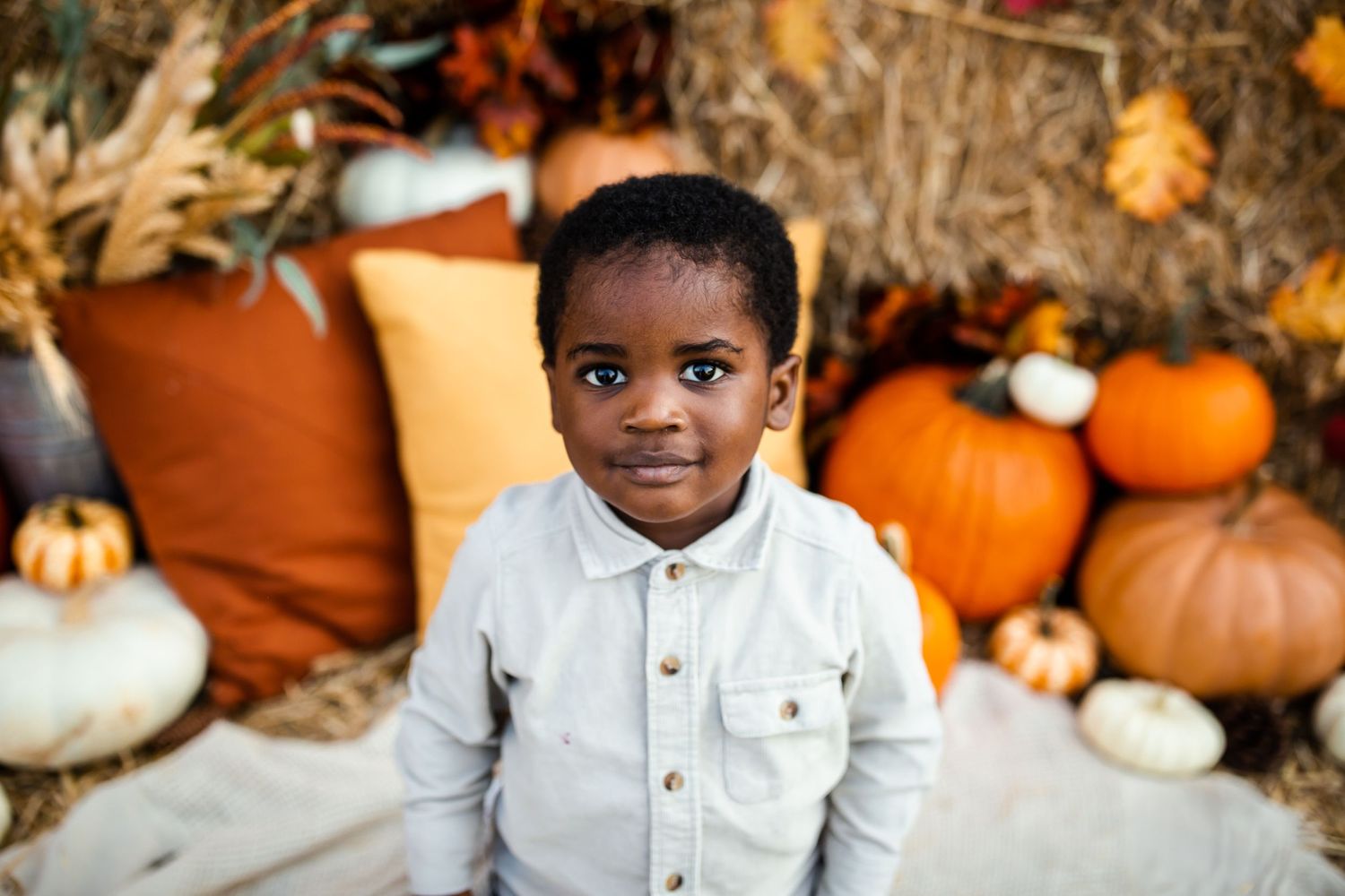 Portrait against a fall backdrop with orange pumpkins and rustic hay bales.