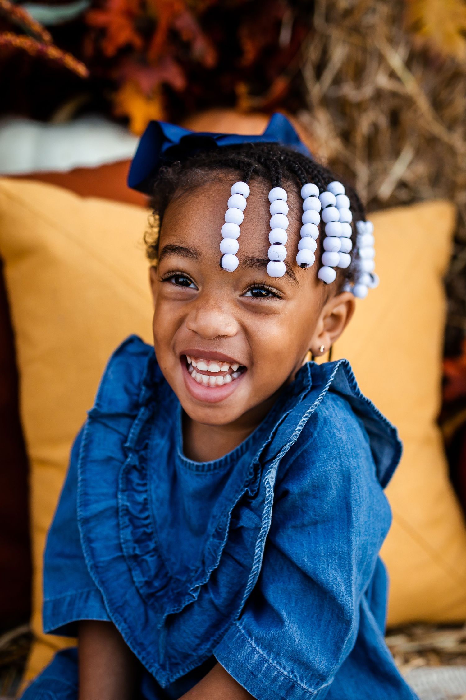 Fall photo setup with denim dress and decorative hair accessories against hay backdrop.