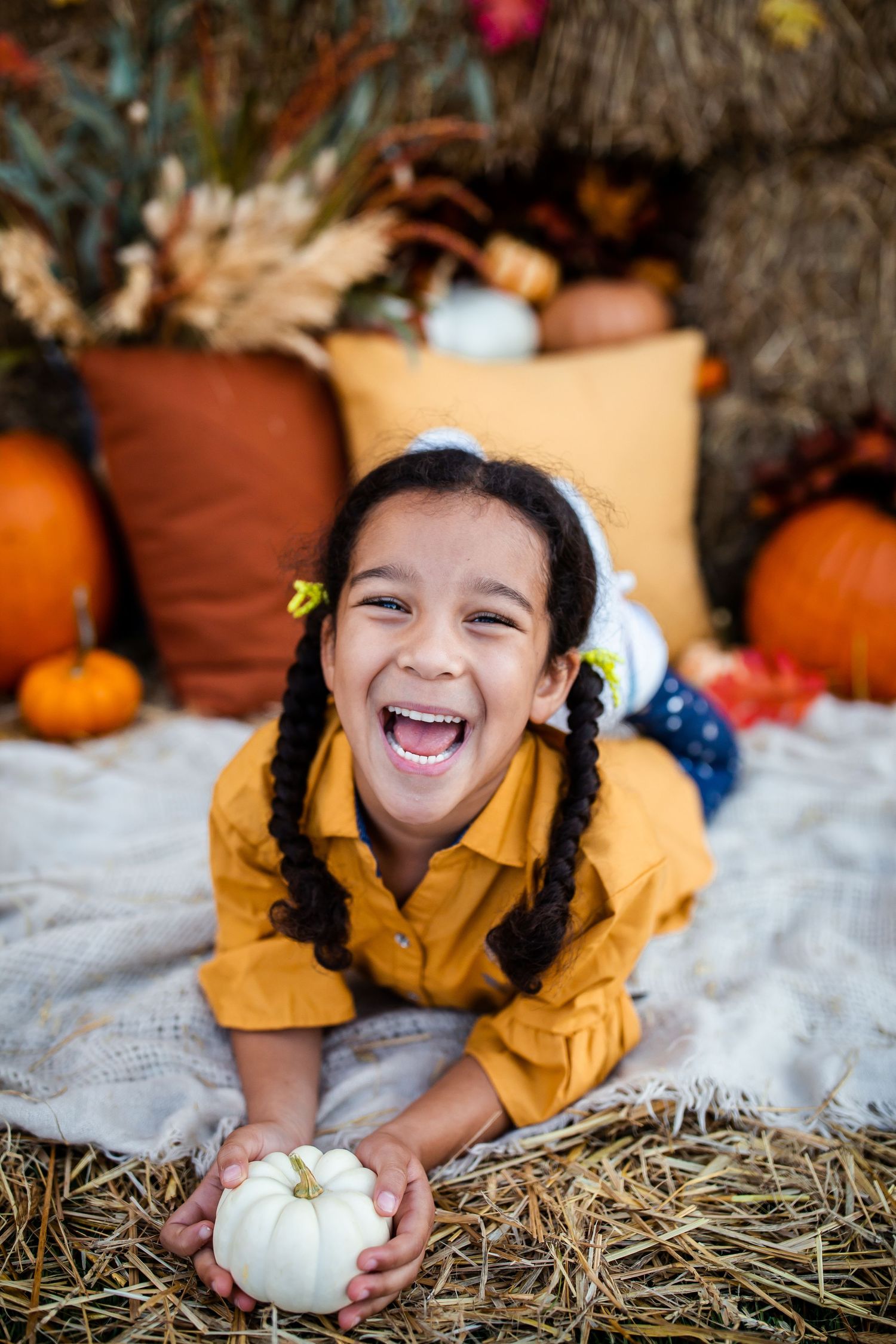 A joyful moment captured in an autumn setting with orange pumpkins and hay bales in the background.