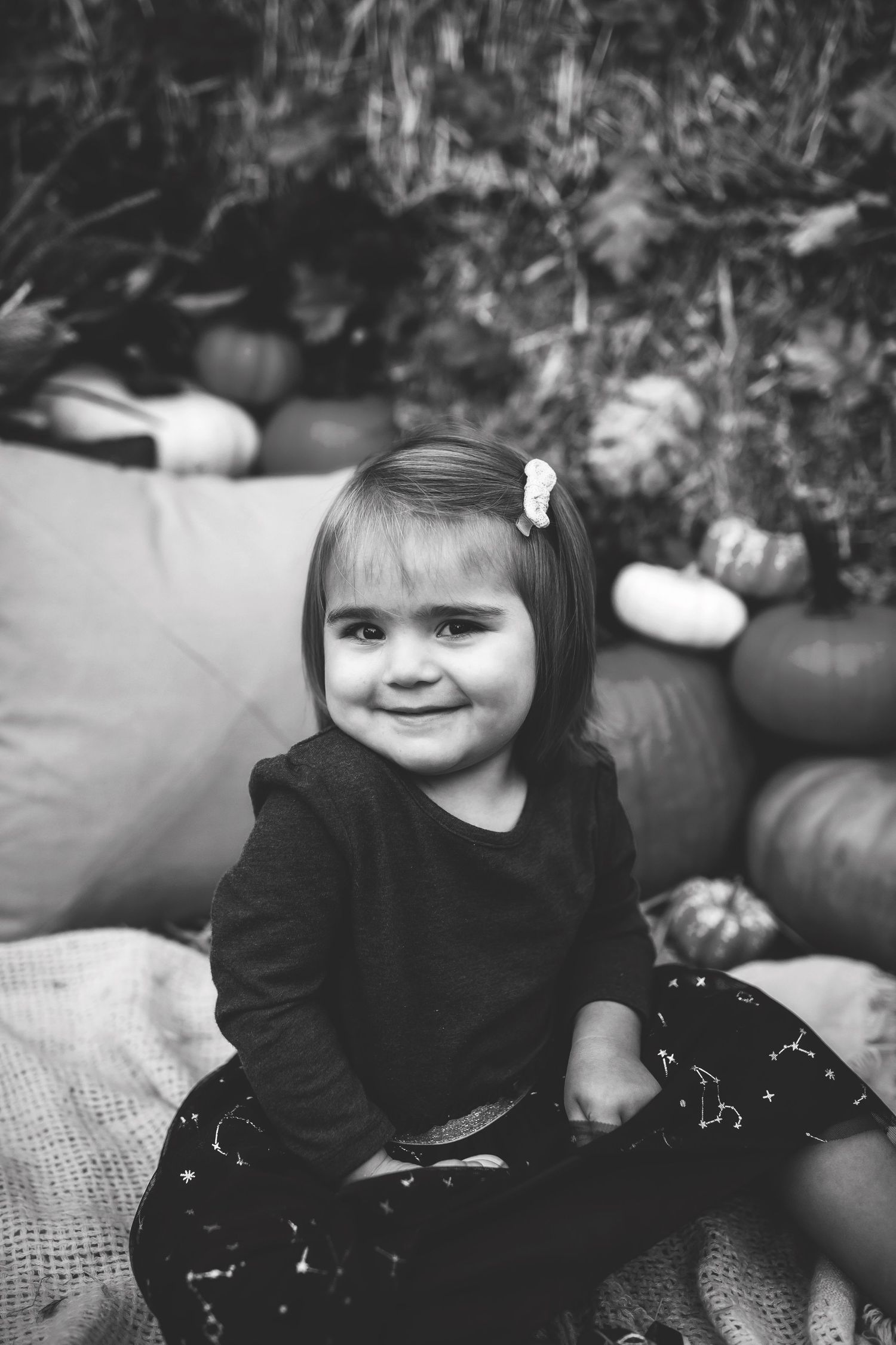 Black and white portrait in front of pumpkins with soft natural lighting.
