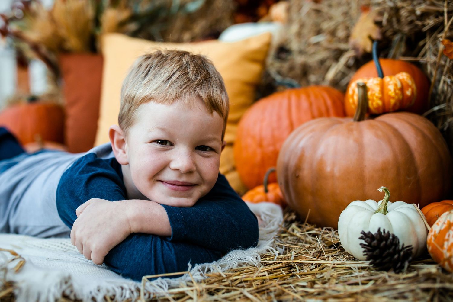 Cozy fall portrait setup with orange pumpkins, hay bales, and rustic autumn decorations.