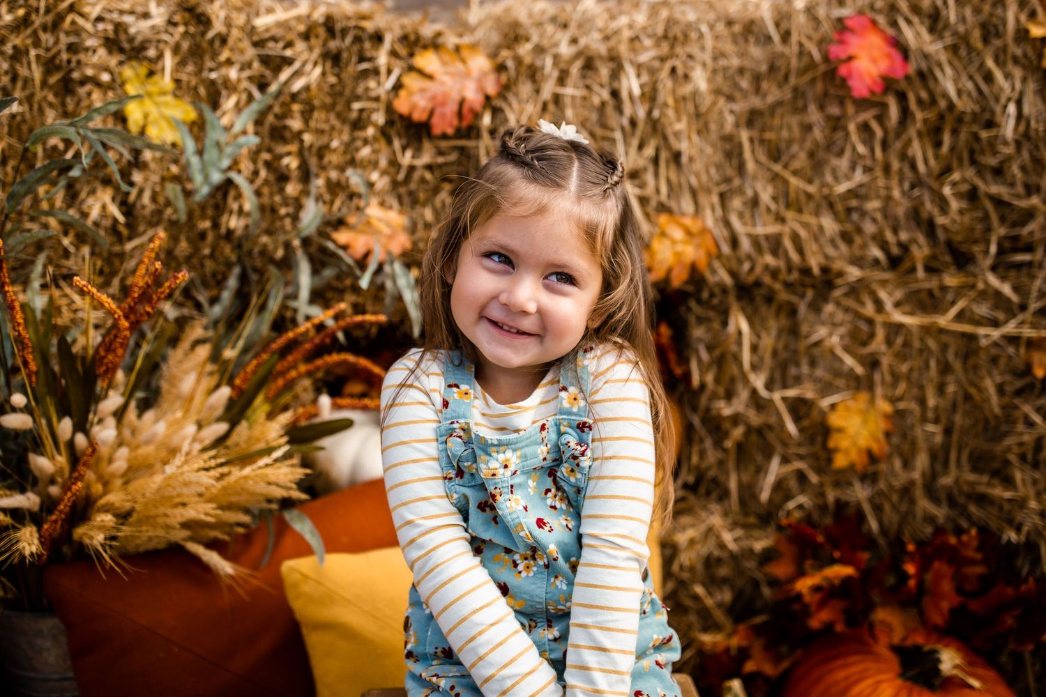 Fall themed photo session with colorful autumn leaves and decorative backdrop.