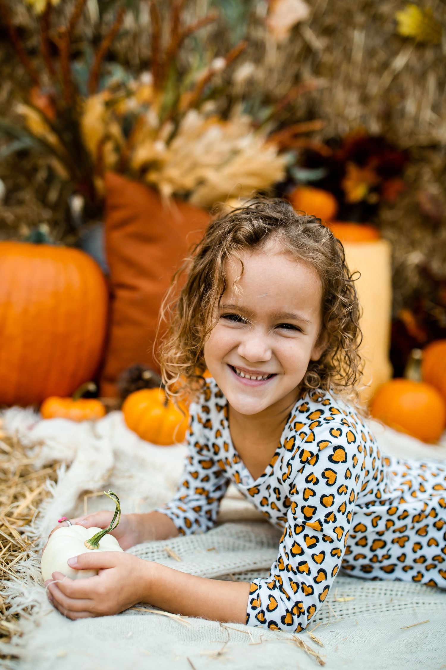 Cheerful autumn portrait with orange pumpkins and decorative gourds in a rustic setting.