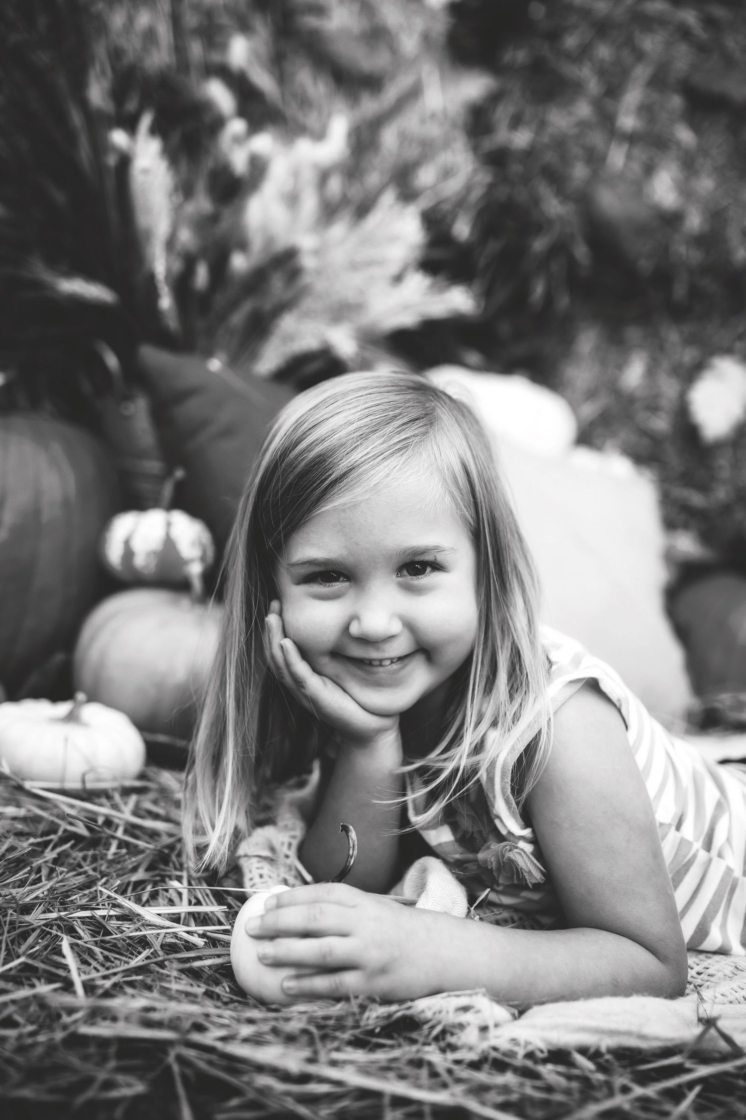 Black and white autumn portrait with pumpkins and natural hay setting.