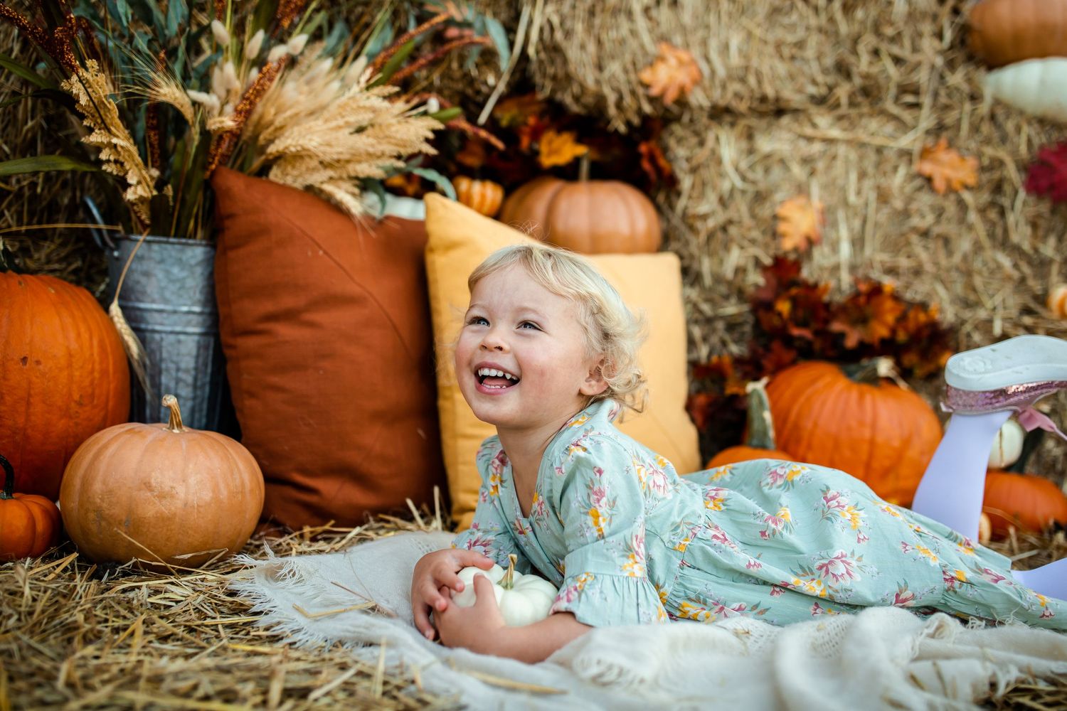 Fall portrait photoshoot with pumpkins, hay bales and smiles against a rustic autumn backdrop.