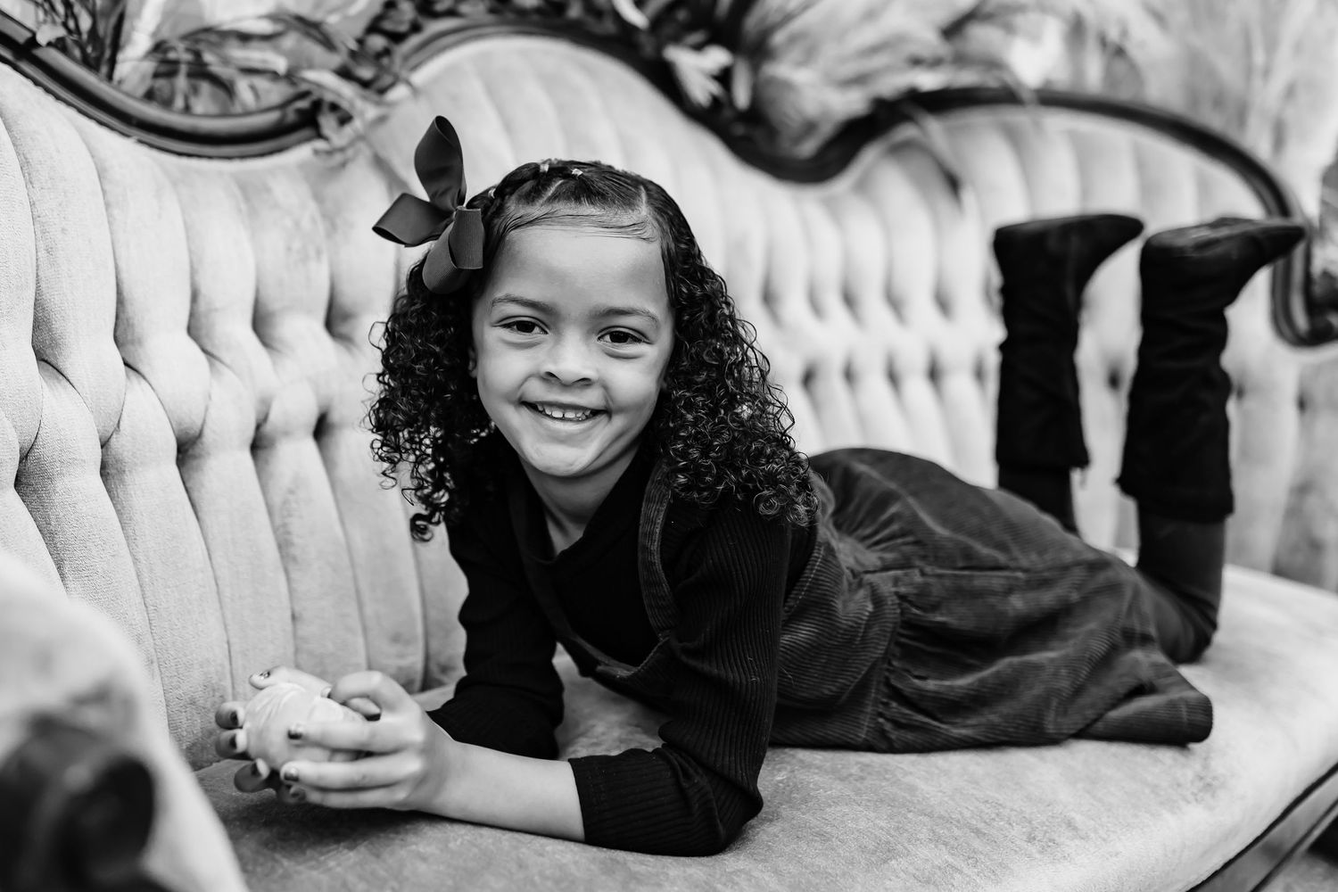 Black and white portrait series of children posing playfully on luxurious vintage furniture.