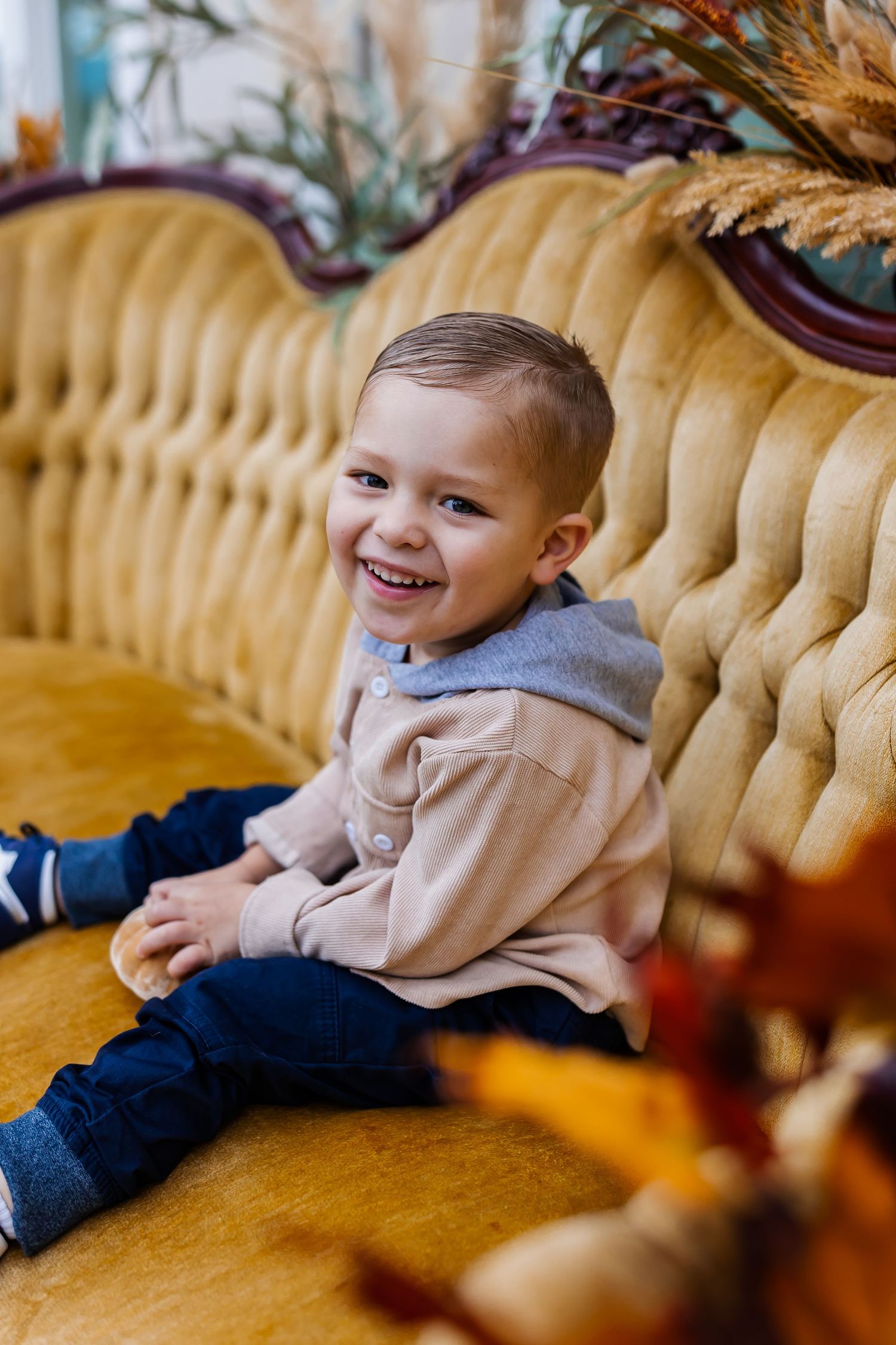A child in casual attire enjoys playtime on a tufted yellow sofa.