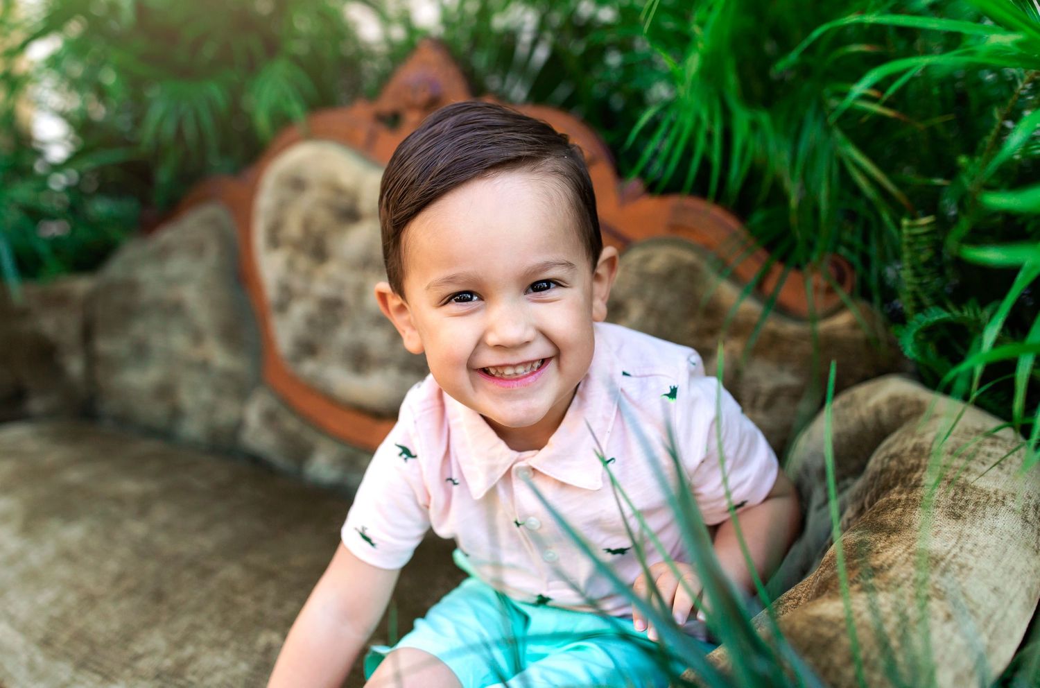 Children having fun posing on outdoor stone furniture with tropical greenery.