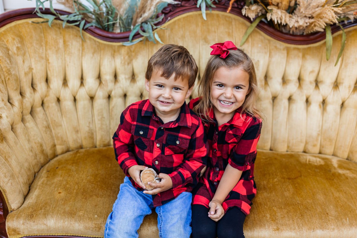 Two children share a joyful moment on a yellow vintage sofa.