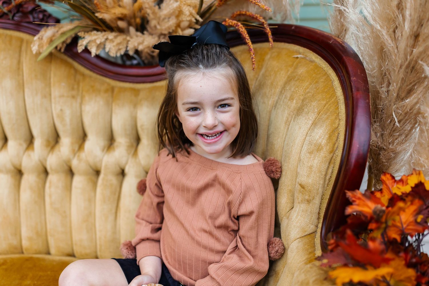 Fall themed photo setup with vintage gold couch and autumn decorations.