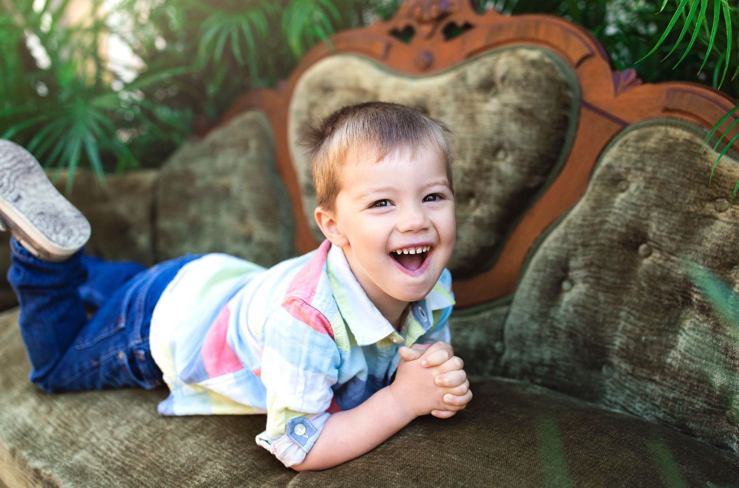 Candid portraits of children laughing and playing on a stone bench with palm plants in the background.