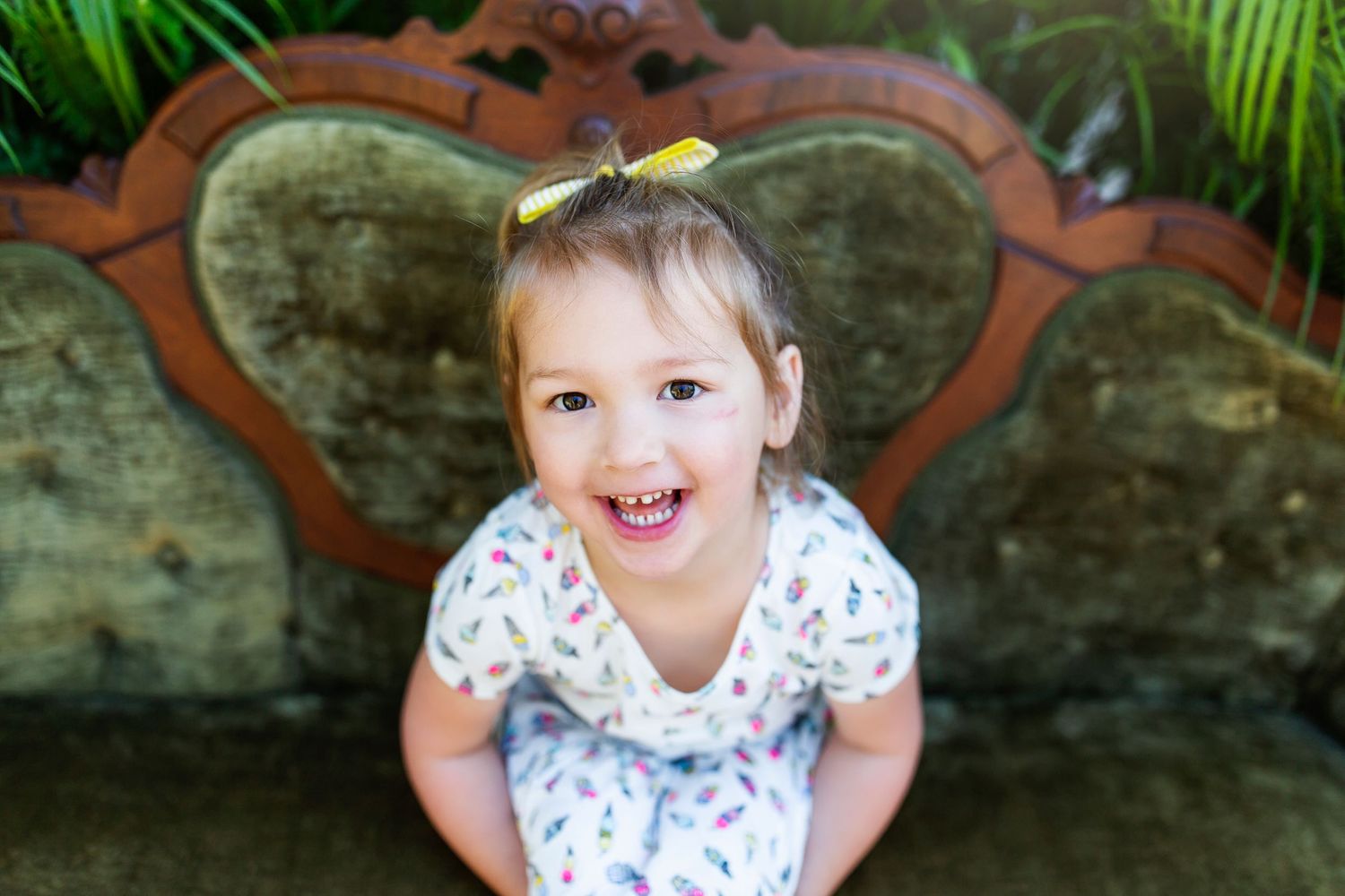 Joyful children posing on stone furniture during a garden photoshoot with tropical plants.