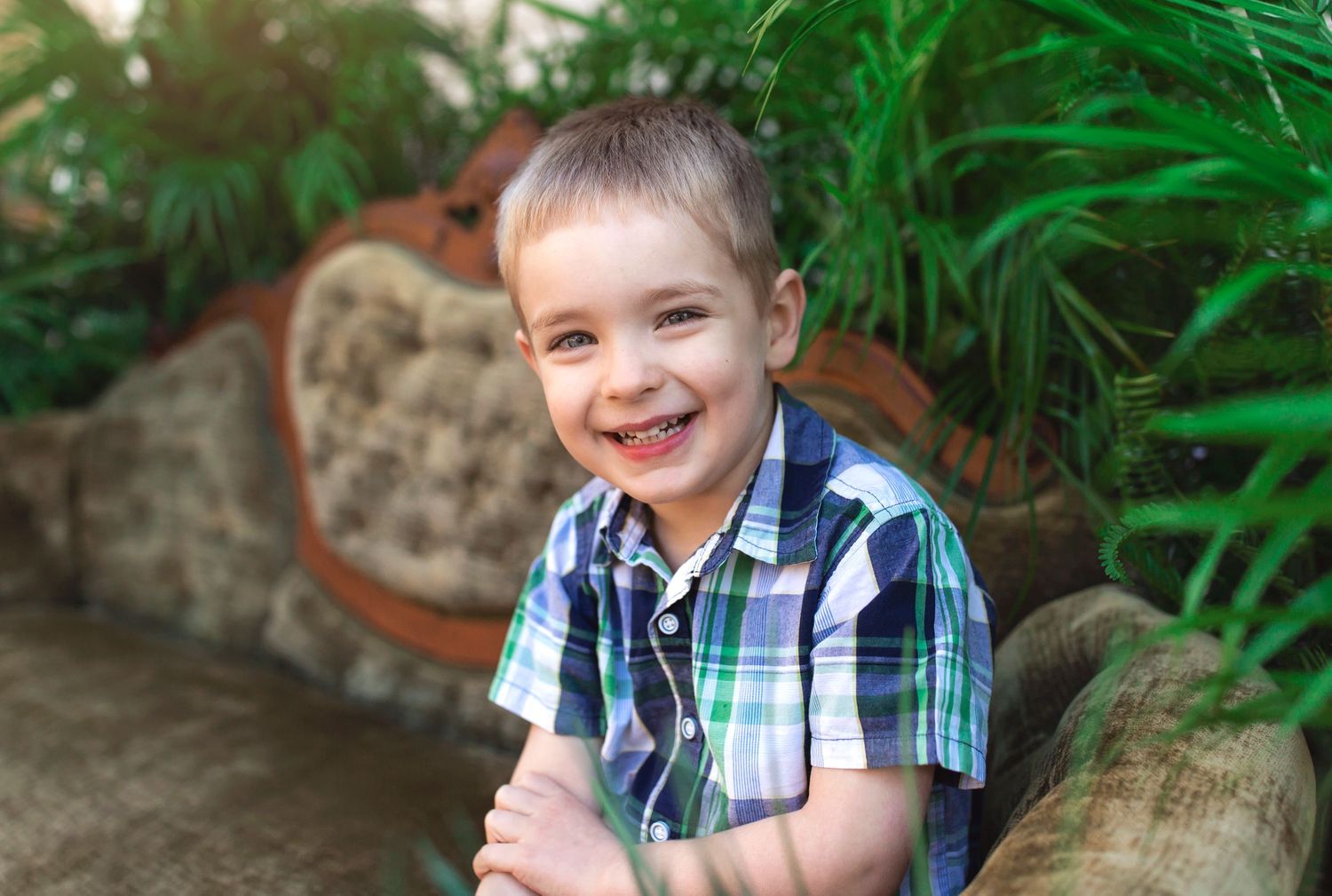 Kids laying on decorative stone furniture surrounded by tropical foliage during an outdoor photo session.
