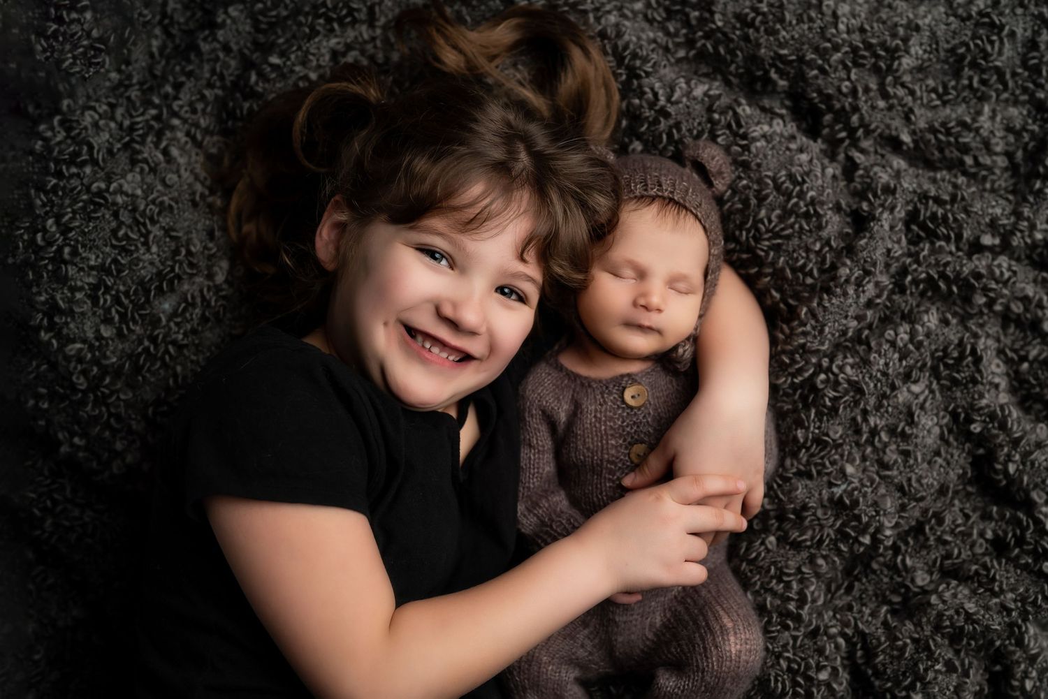 Family portrait on black textured backdrop with dramatic lighting.