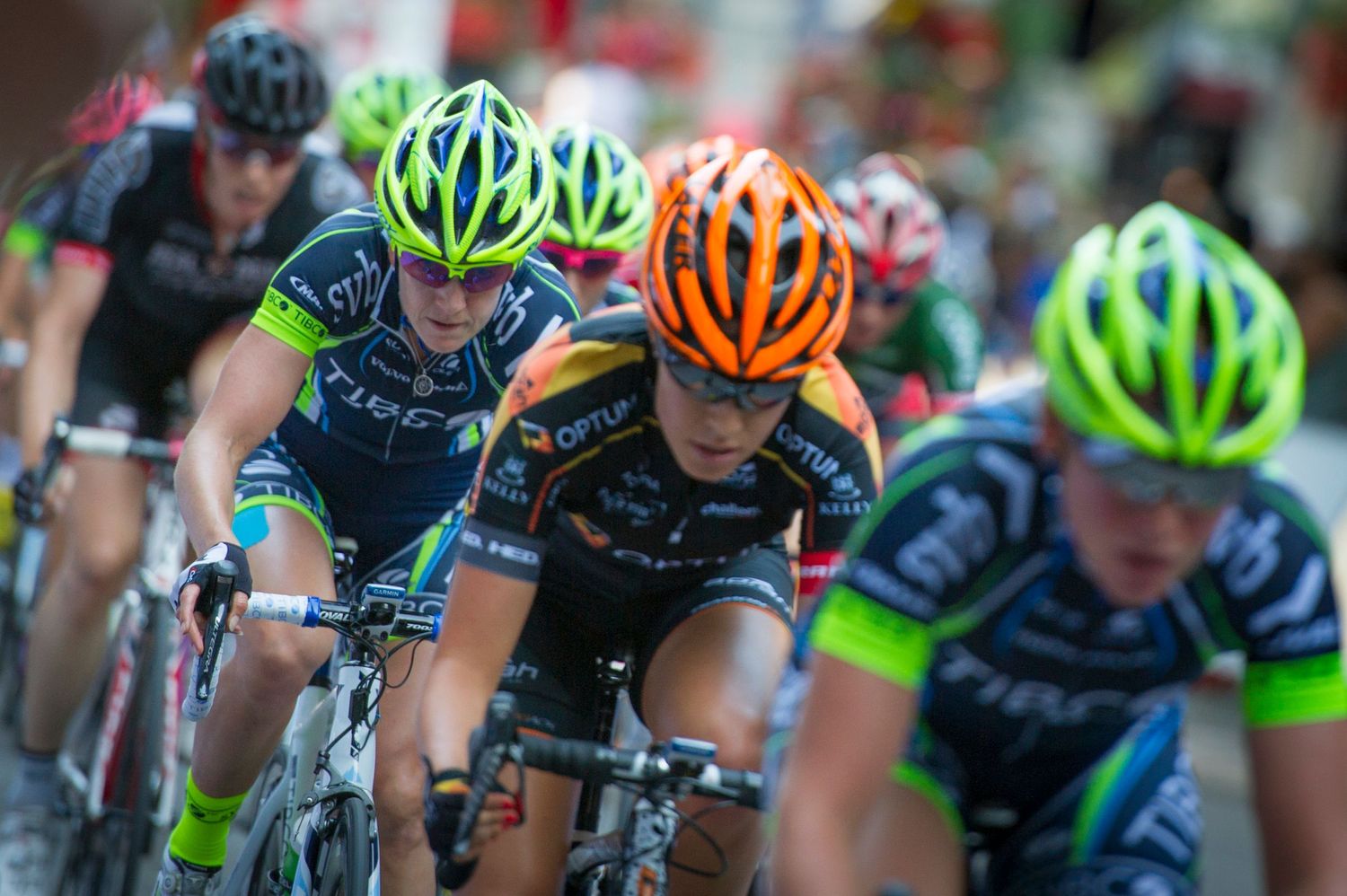 Cyclists in bright helmets race in close formation during a competitive cycling event.