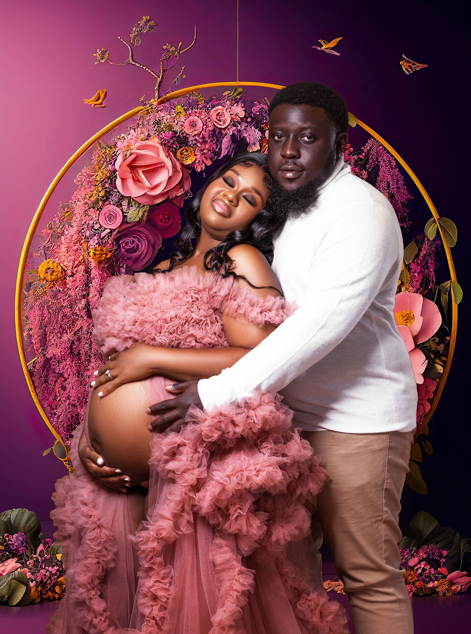 Romantic maternity photo with floral circle arch and pink tulle dress against purple background.