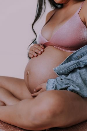 Intimate pregnancy photo showing bare belly with soft lighting and grey fabric.