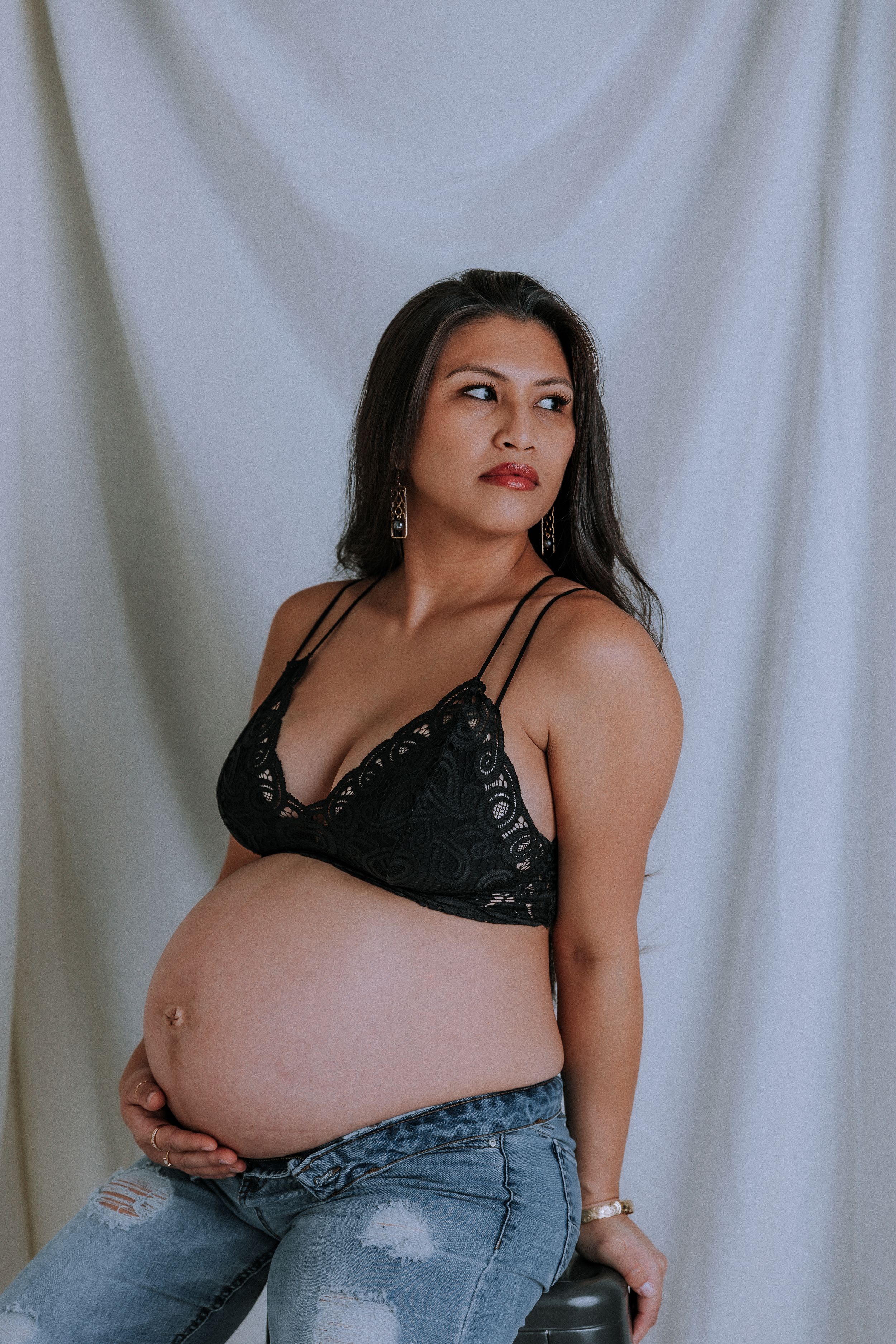 Maternity studio session with dramatic lighting and denim styling.