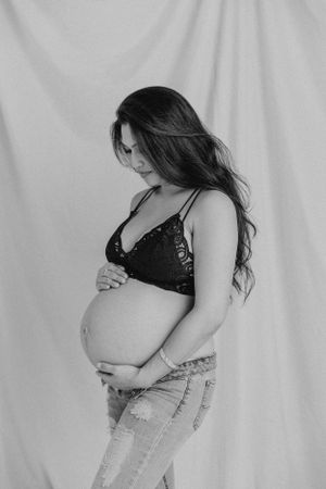 Side view maternity portrait in monochrome against white background.