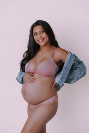 Maternity photoshoot in pink bra and denim jacket showing candid poses.
