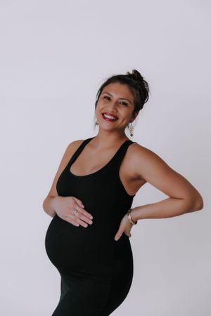 Candid pregnancy photos showing happy expressions and natural poses in studio lighting.