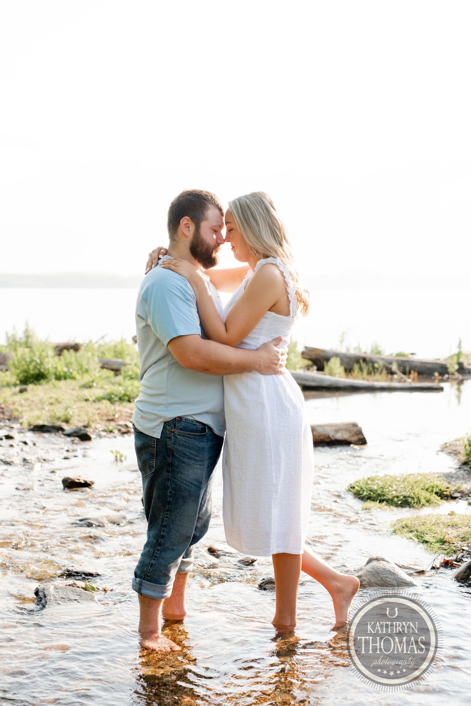 A romantic moment shared at the water's edge during a sunny day.