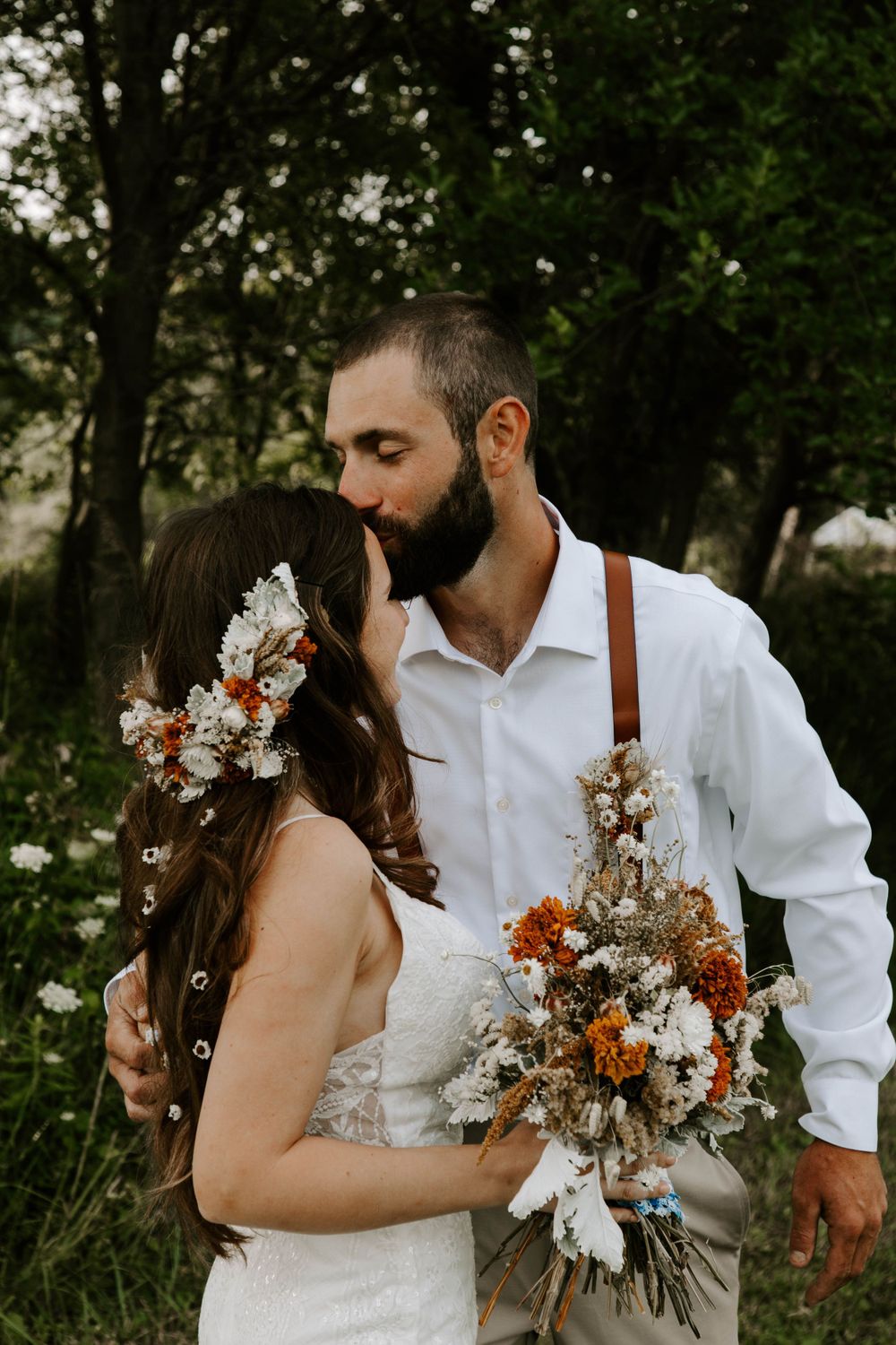 Intimate wedding portrait with rustic floral bouquet in woodland setting.