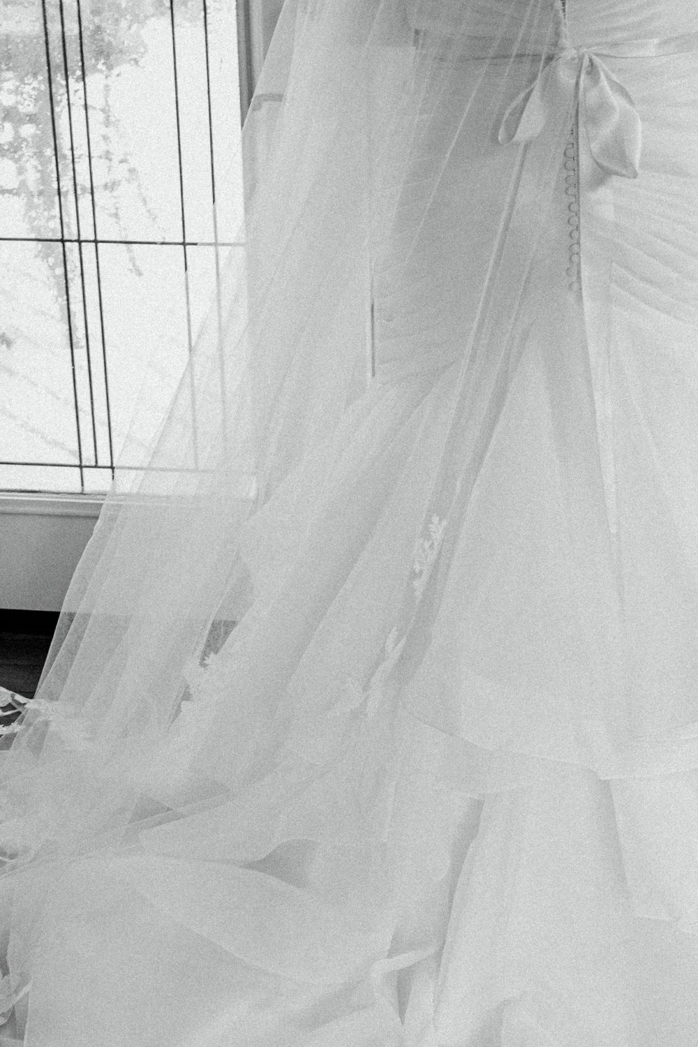 Close-up of flowing white wedding dress veil details in black and white.