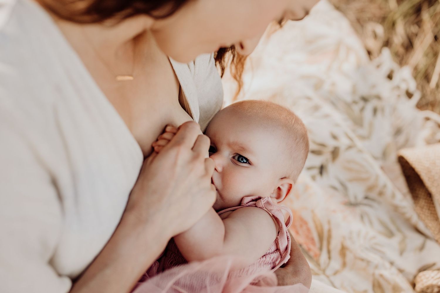 Intimate motherhood moment of breastfeeding captured in soft natural light.