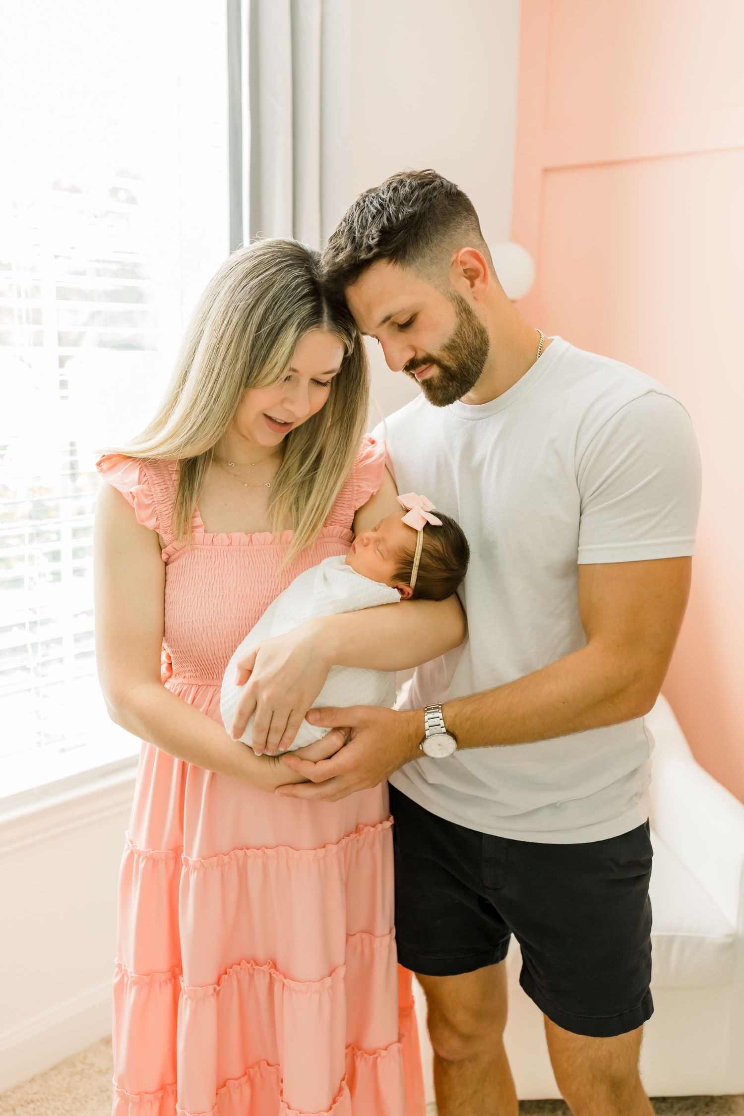 Sweet family moment by window in coral-colored nursery.