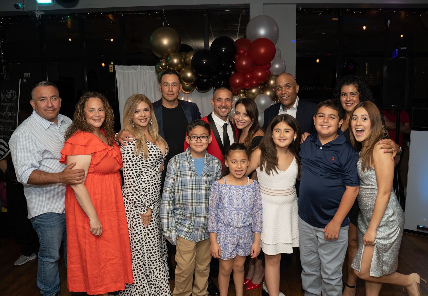 Extended family and friends posing together at formal celebration event.