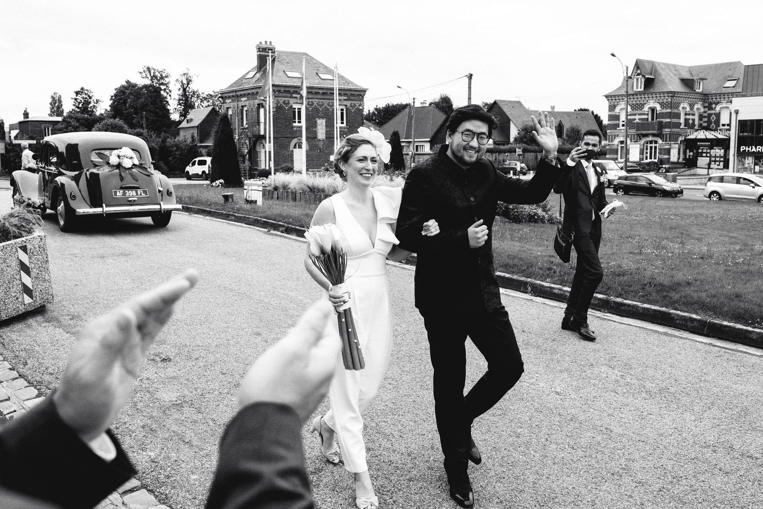 Vintage black and white photo of celebration on suburban street with classic cars.