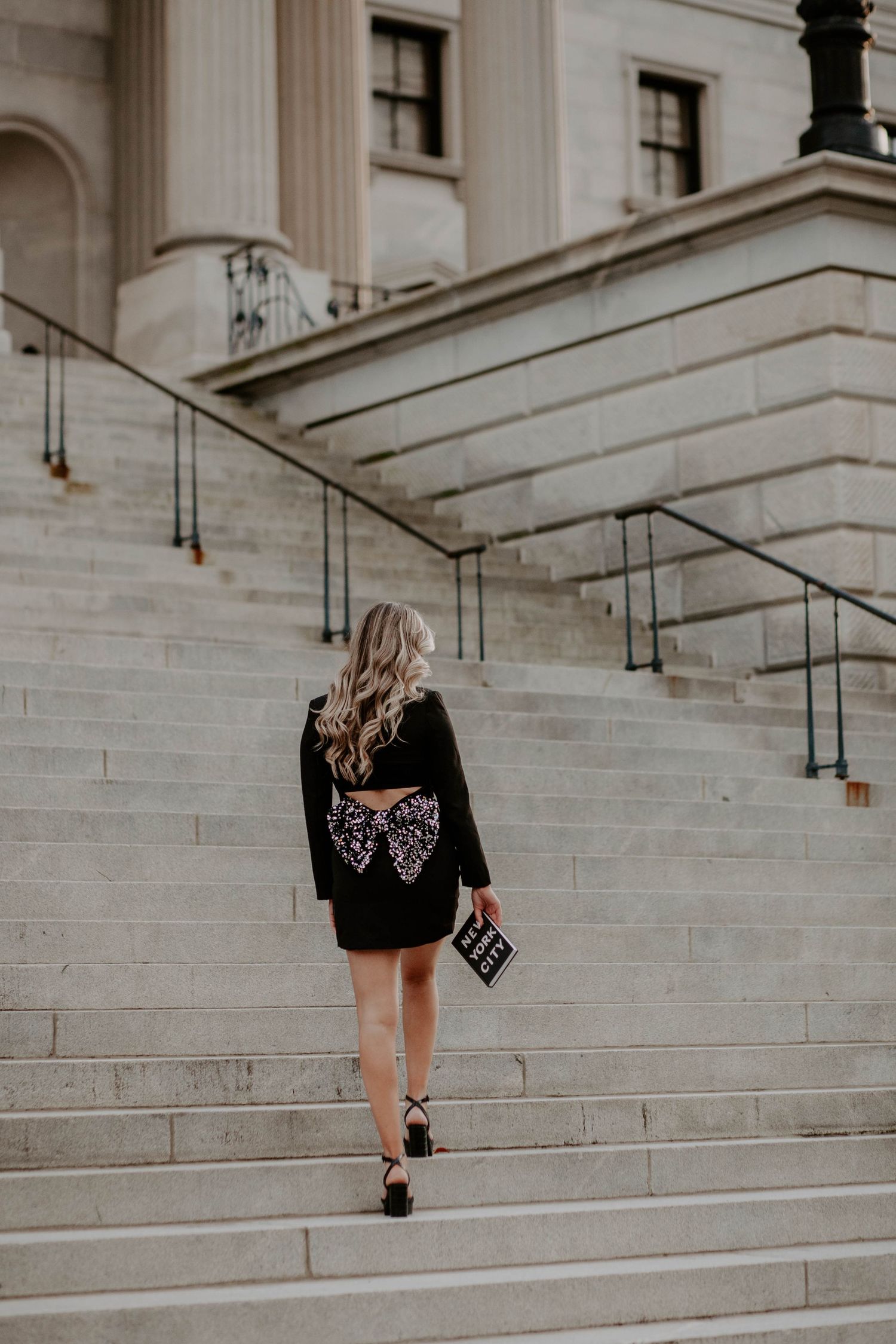 Senior portrait of girl walking up steps holding a book on New York City.