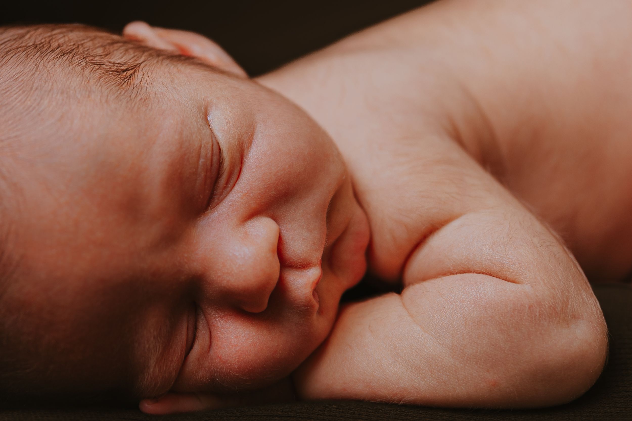Soft focus close-up of a sleeping newborn in warm lighting.
