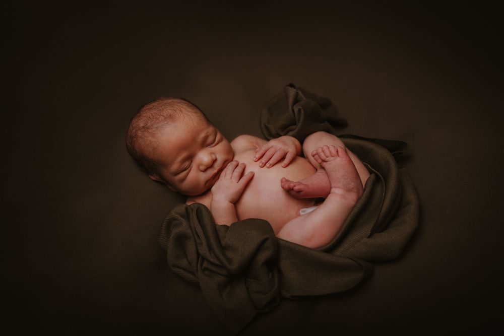Artistic newborn photography with gentle shadows and soft lighting.