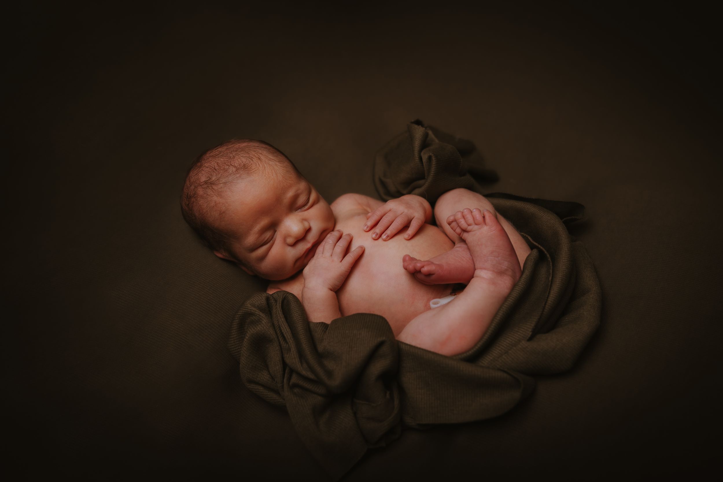 Artistic newborn photography with gentle shadows and soft lighting.