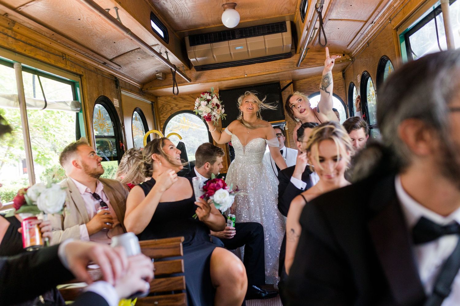 Joyful celebration inside vintage trolley with wedding party raising glasses.