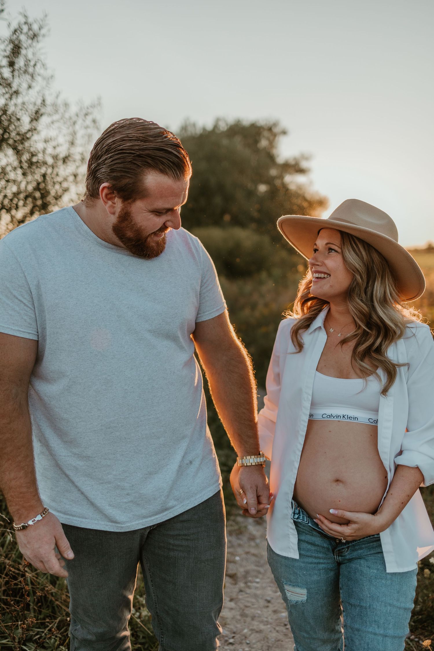 Expecting couple shares tender moment during sunset maternity photoshoot.