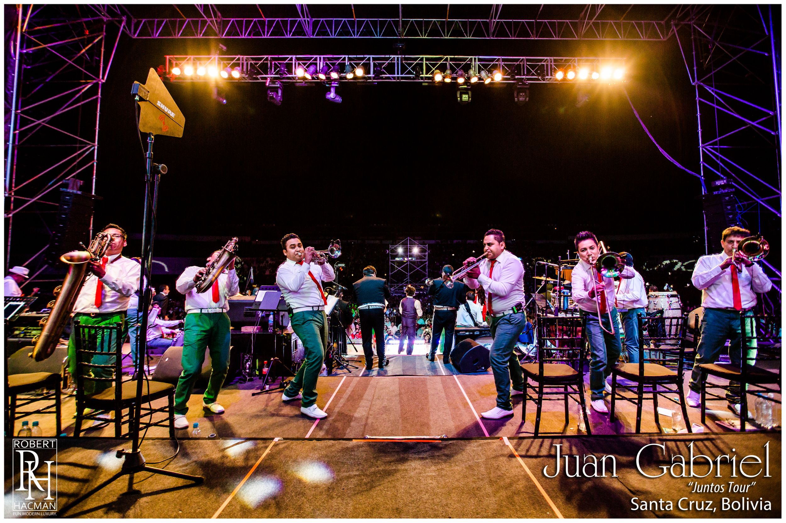 Wide shot of concert stage with performers and warm ambient lighting.