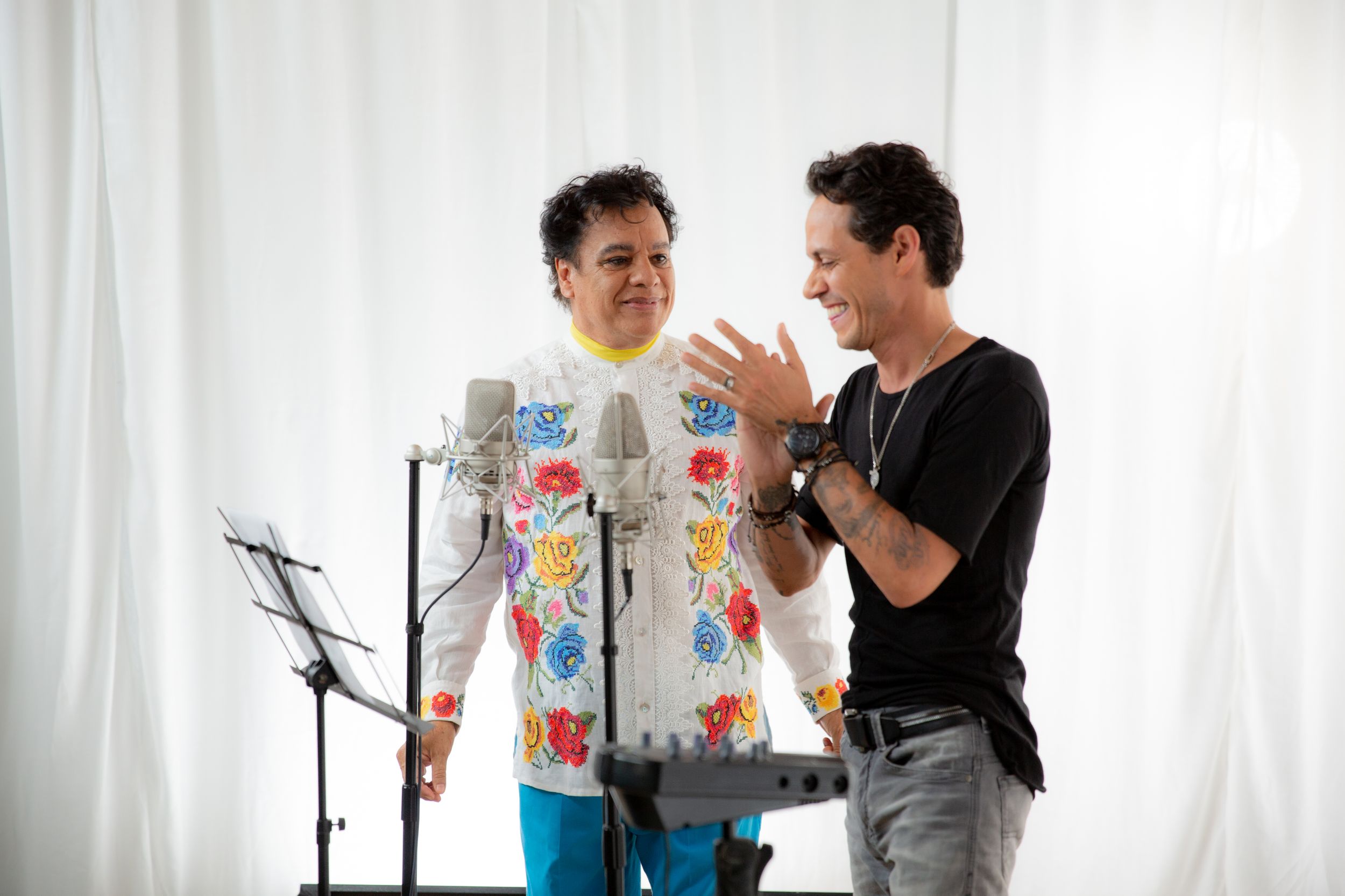 Candid interaction during recording studio session with white backdrop.