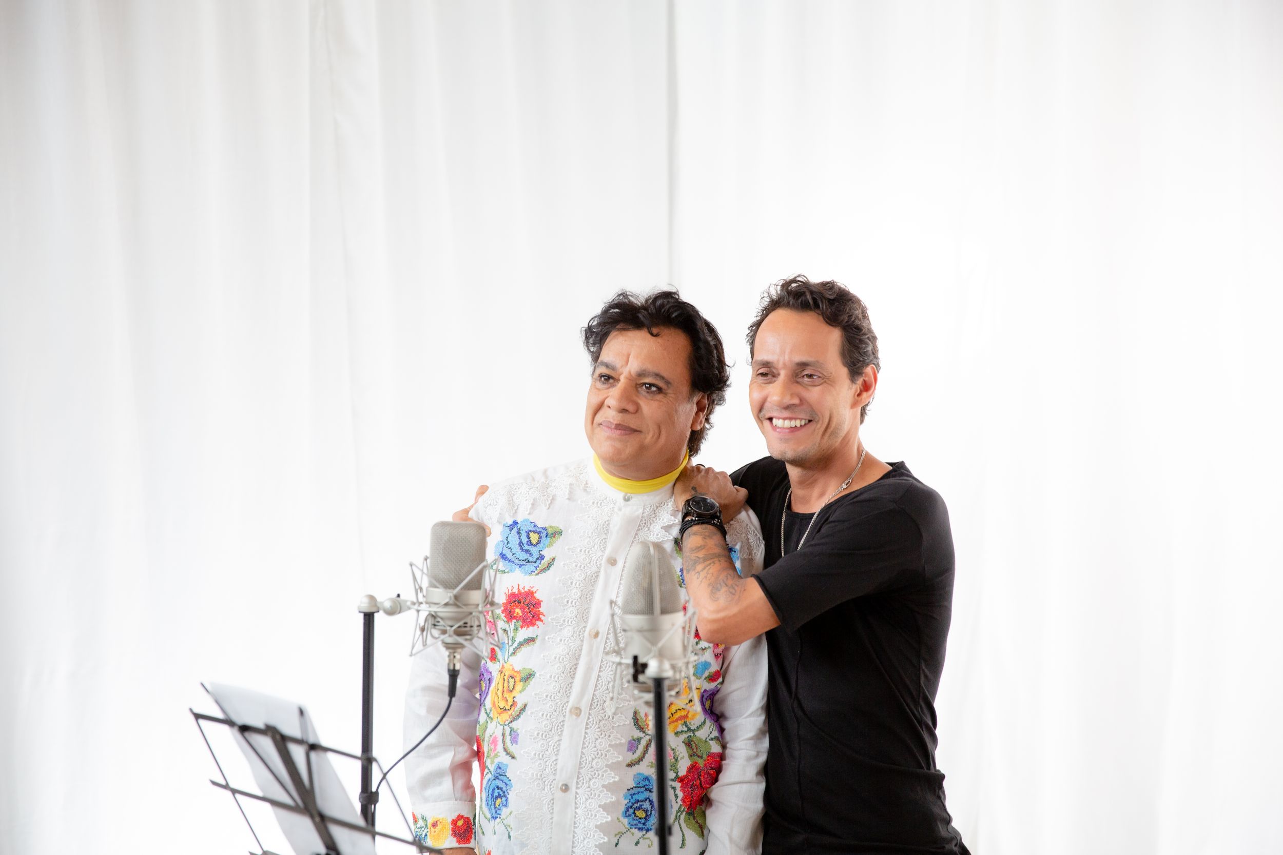 Recording studio session with microphone setup and white backdrop.