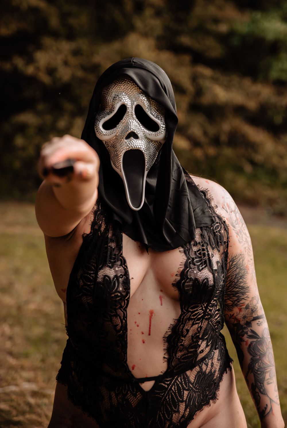 Halloween-themed photoshoot featuring a Scream mask and black lace in woodland setting.