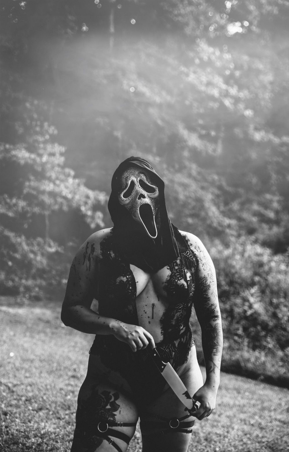 Black and white horror-themed photography with dramatic lighting in outdoor setting.