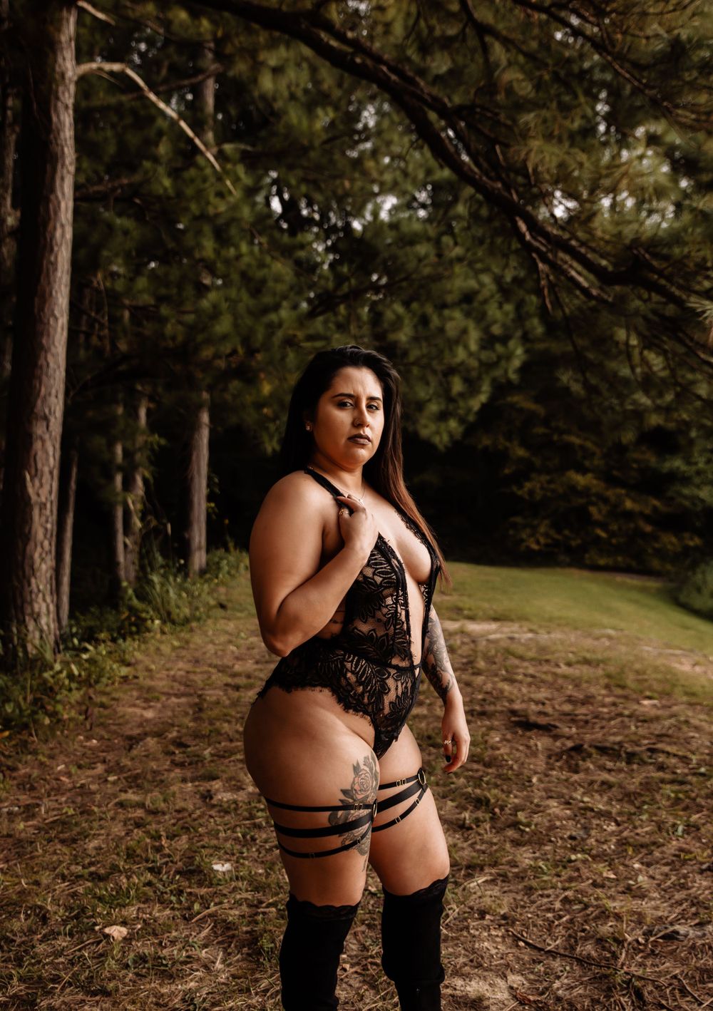 Artistic boudoir photoshoot in a wooded forest setting with dramatic lighting and dark aesthetic.