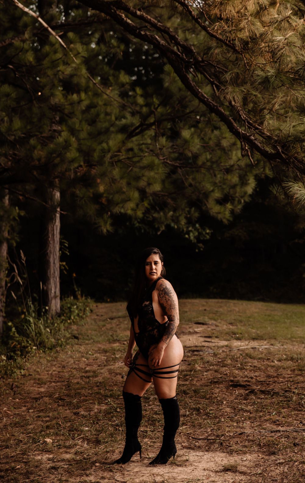 Moody outdoor portrait session with dark tones among tall pine trees.