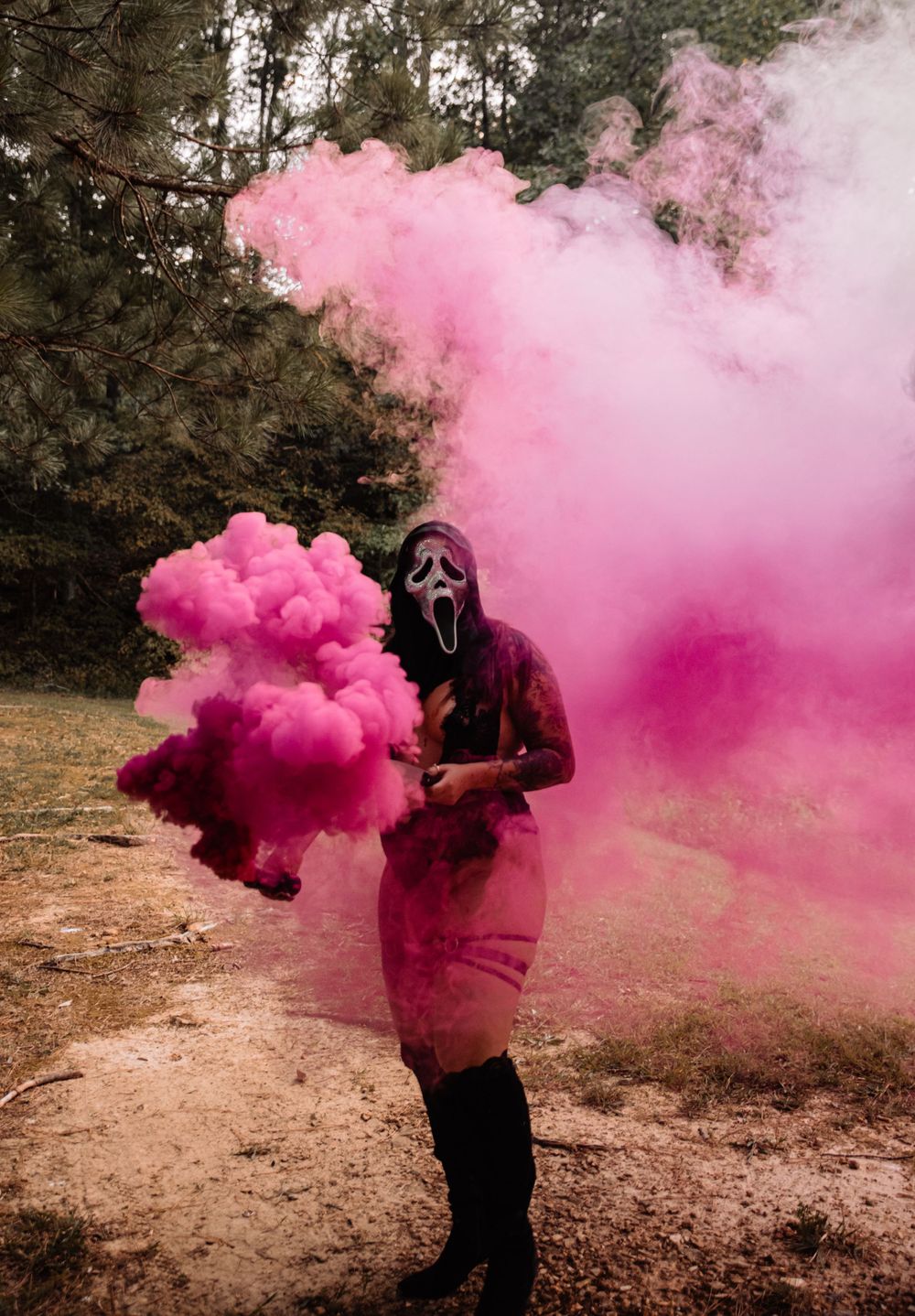 Artistic photoshoot featuring bright pink smoke bombs in a forest clearing.