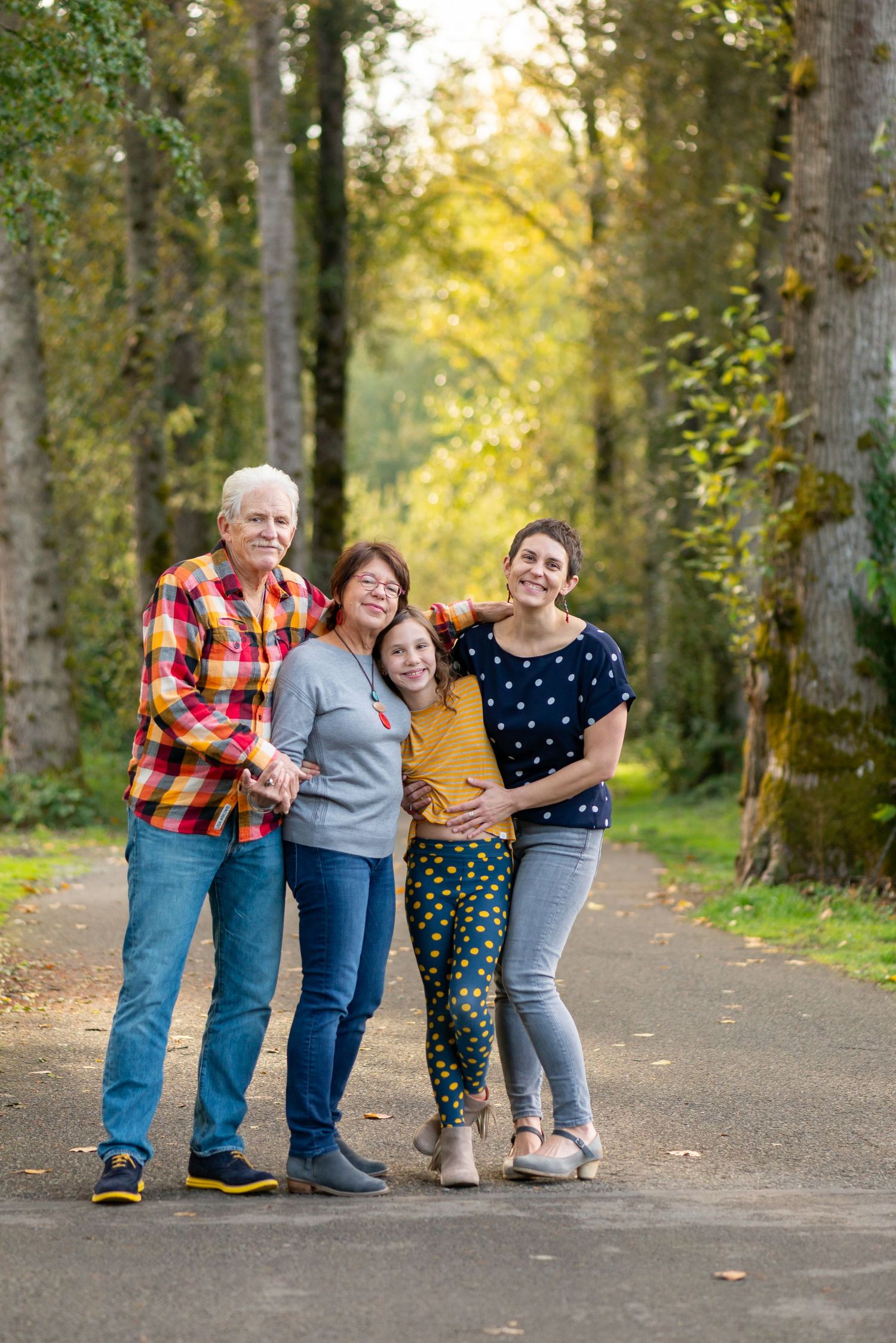 Family enjoying a casual photo session on a tree-lined path during golden hour.