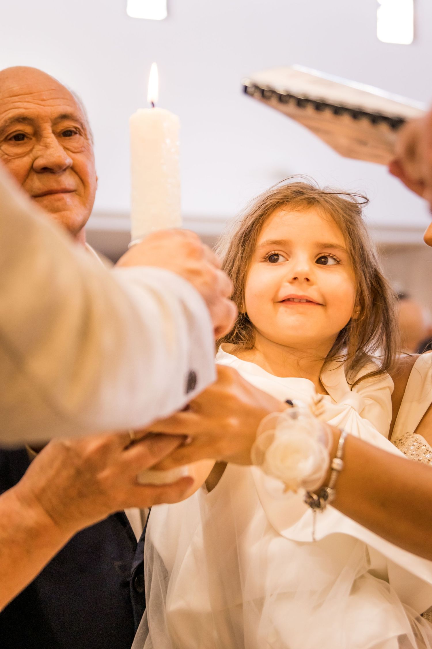 A series of photos capturing a child in a white dress during a religious ceremony.