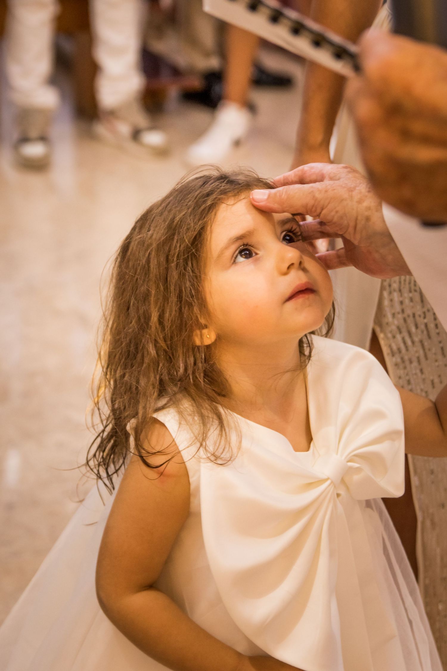 Sequential shots of a young child in white during a special ceremony.