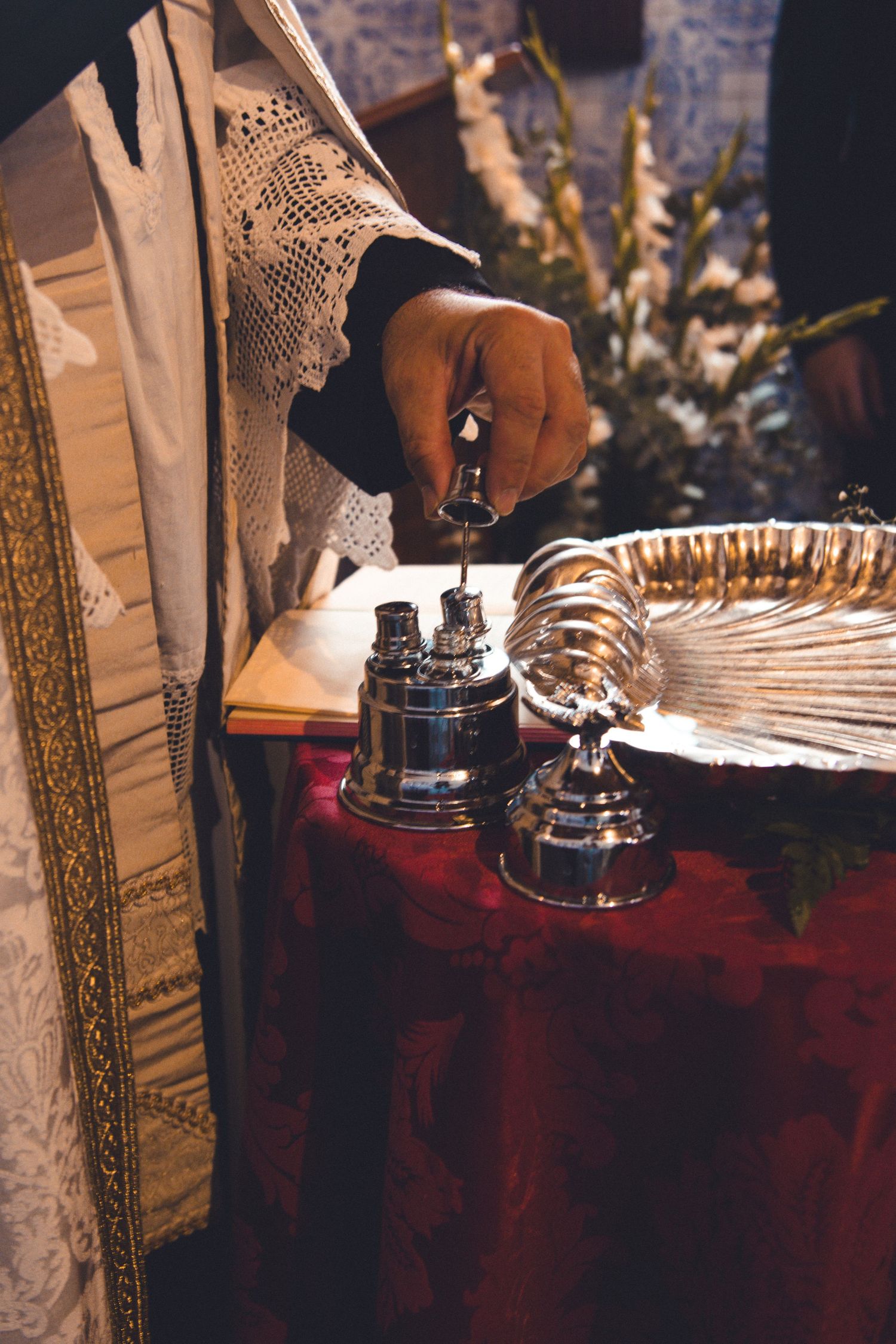 Detail shot of ceremonial items on a red cloth-covered table during a religious service.